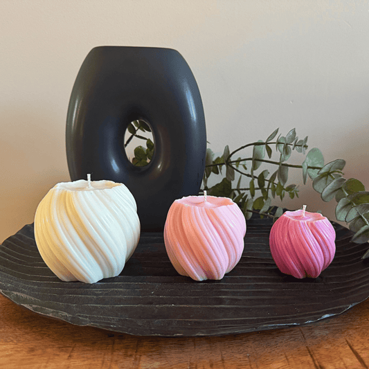 Drie kaarsen van groot naar klein op een zwarte schaal.