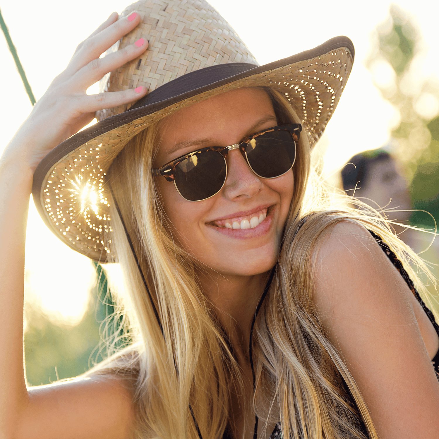 Lachende vrouw met zonnebril en cowboyhoed.